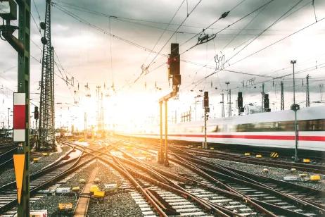 Gleise und Gleiskreuzungen vor Bahnhof mit vorbeifahrenden Zug