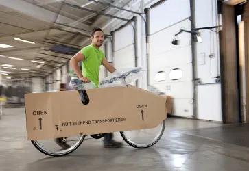 Logwin Mitarbeiter schiebt ein verpacktes Fahrrad